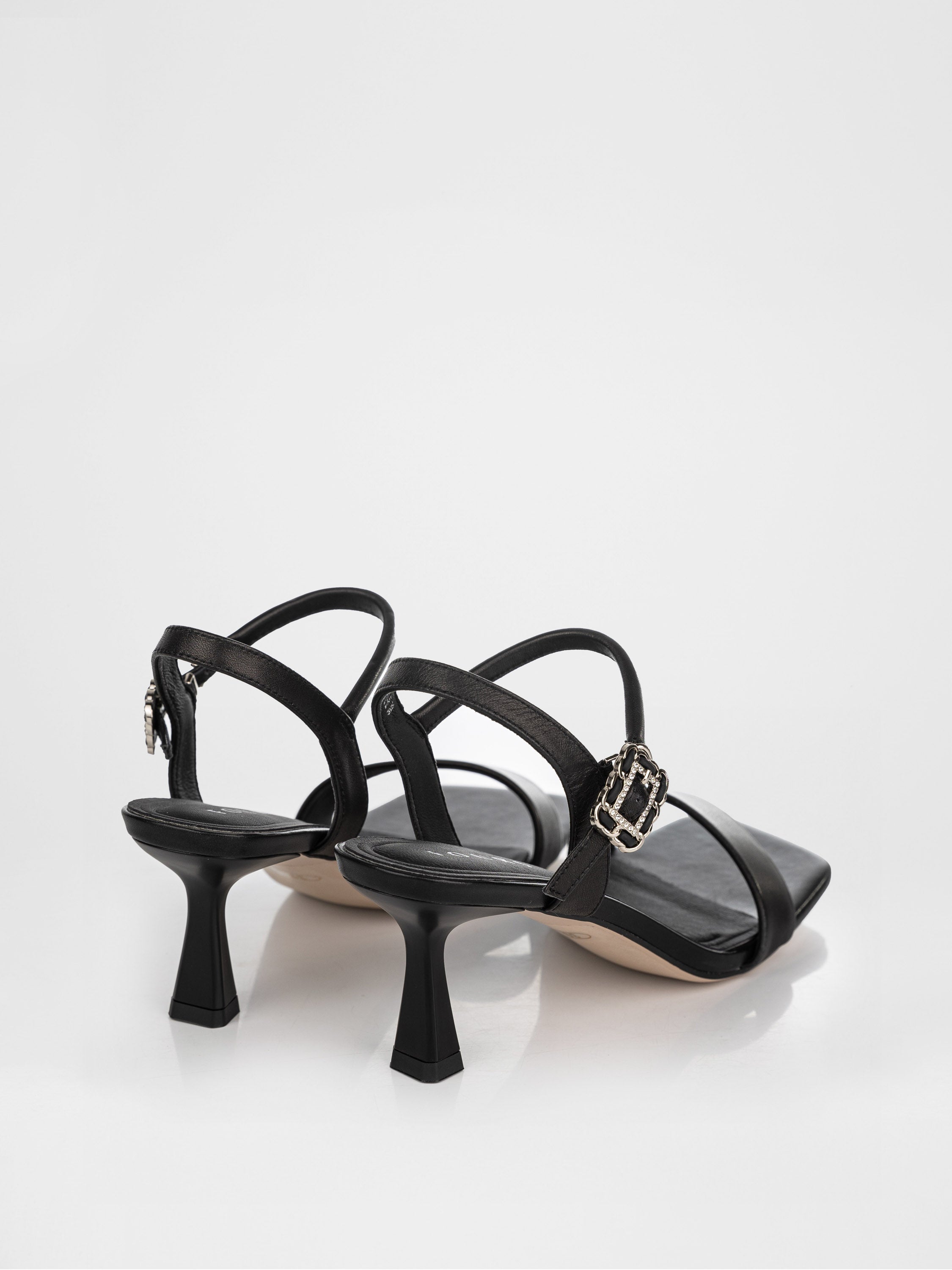 Sandalias de tacón negras decoradas con una hebilla con piedras.